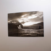 A black and white tempered glass wall art featuring a wave, with a high-gloss finish, mounted on a wall.