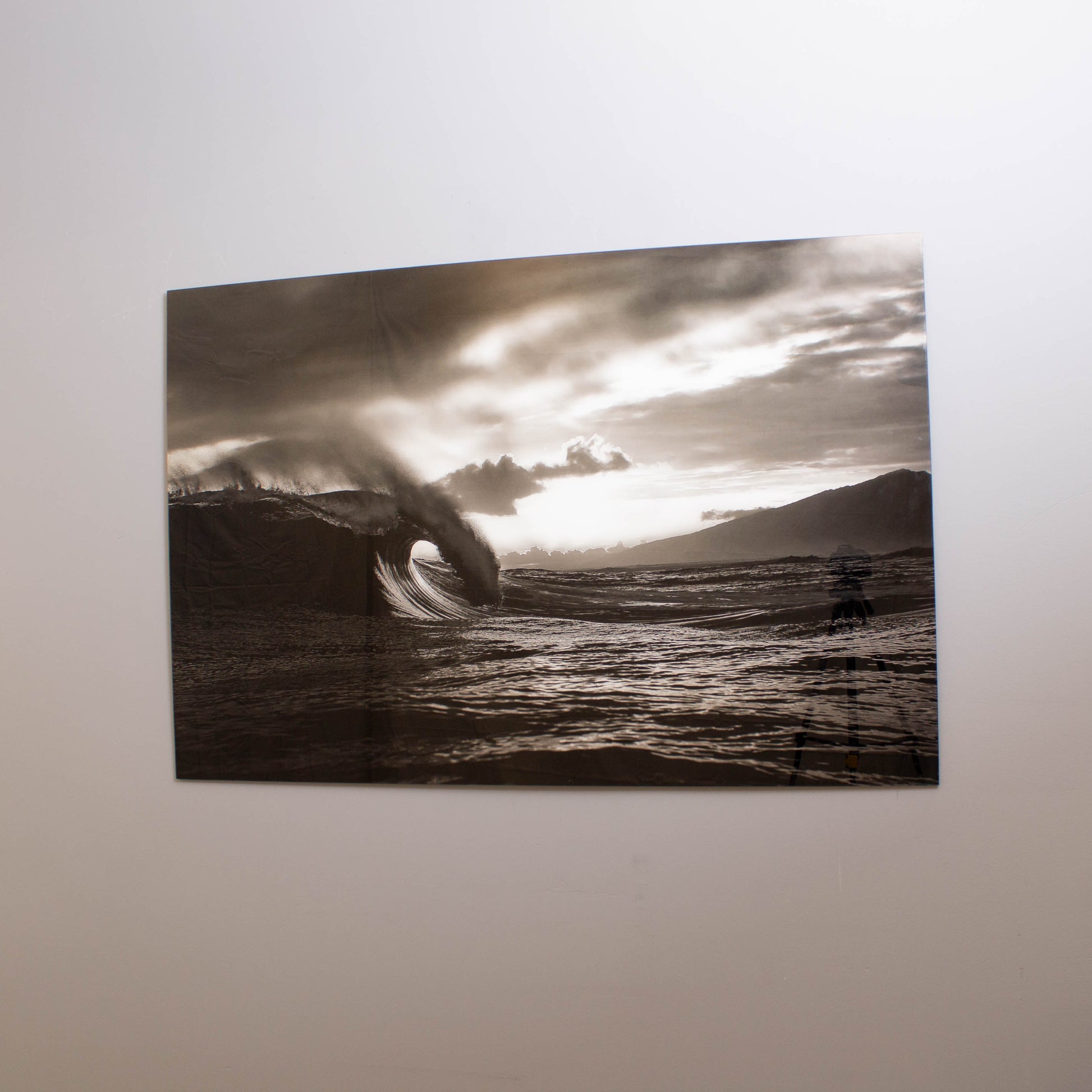A black and white tempered glass wall art featuring a wave, with a high-gloss finish, mounted on a wall.